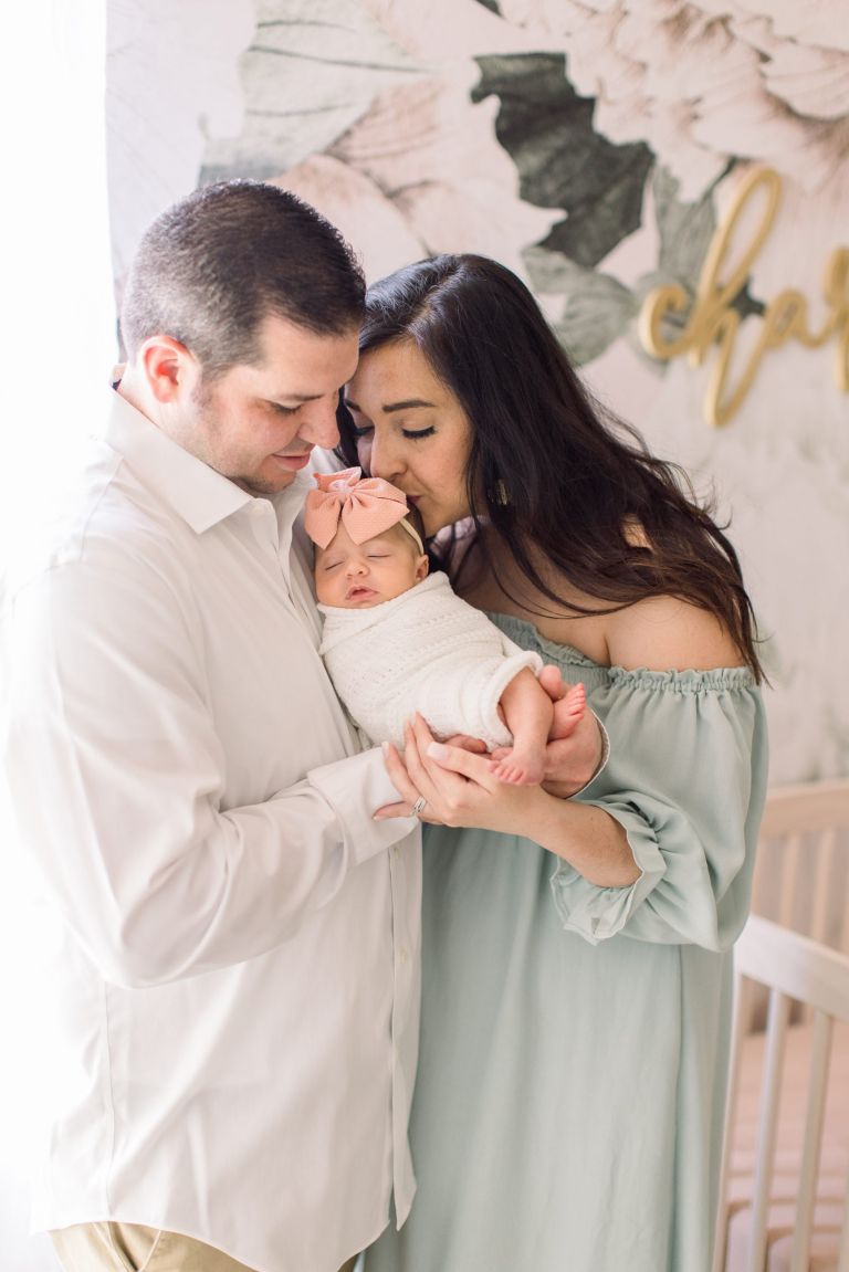 Mom kissing newborn in nursery during a photoshoot at their OKC home.